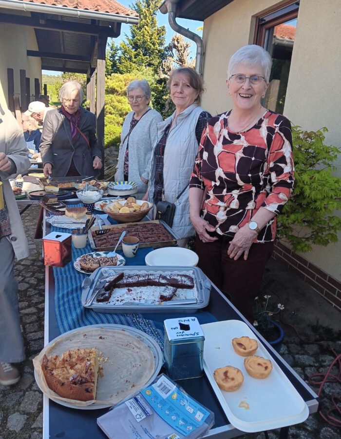 Mitglieder stehen lächelnd hinter einem Tisch mit selbstgebackenem Kuchen