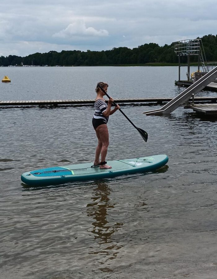 Ein Mitglied steht auf einem Stand-up-Paddle-Board auf dem See