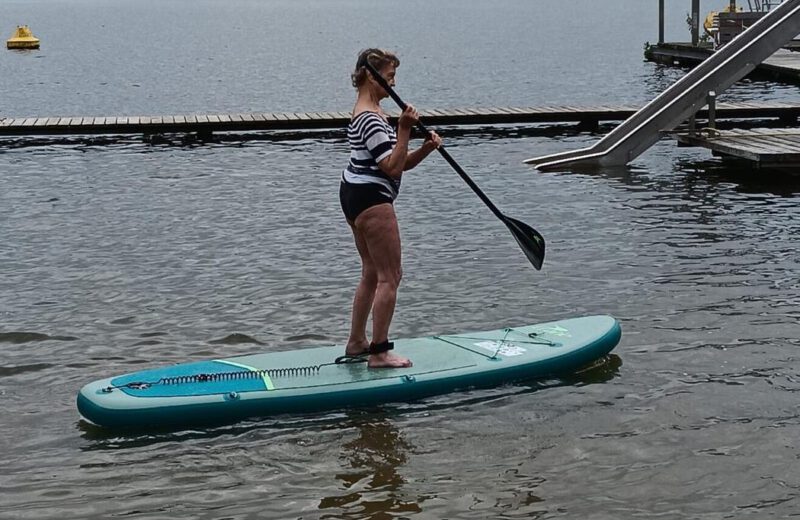 Ein Mitglied steht auf einem Stand-up-Paddle-Board auf dem See